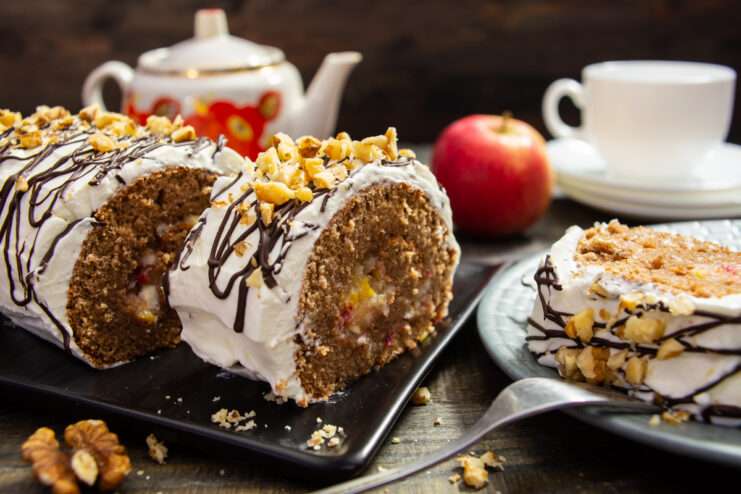 Brazo de gitano de chocolate relleno de frutas y crema, decorado con hilos de chocolate y nueces troceadas.