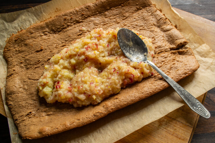 Bizcocho desenrollado con el relleno de puré de frutas extendido por encima.