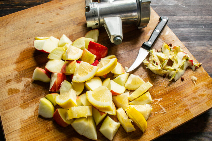 Trozos de manzana y limón cortados sobre una tabla de madera listos para triturar.