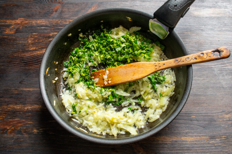 Cebolla pochada mezclada con cilantro fresco picado en una sartén