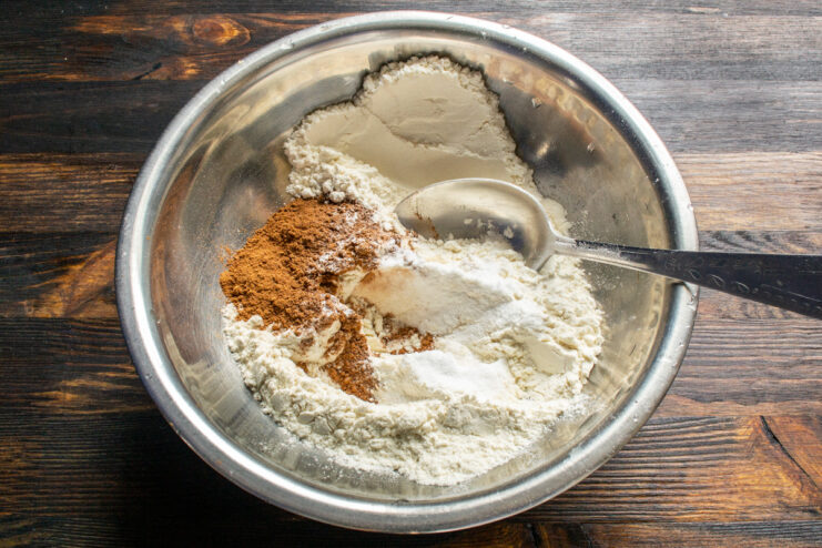 Mezcla de harina de trigo, cacao en polvo, canela y levadura química en un bol metálico.
