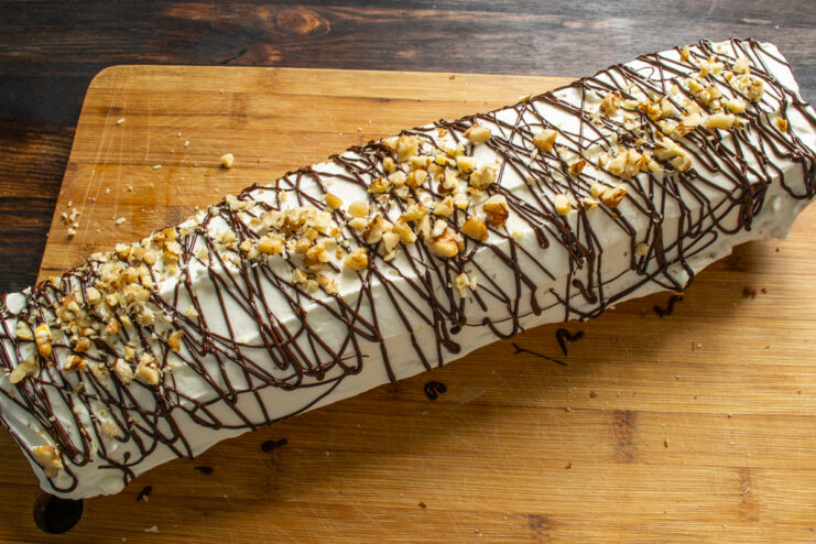 Detalle del brazo de gitano decorado con chocolate fundido y trocitos de nuez esparcidos.