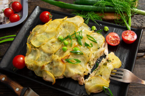 Pechuga de pollo al horno bajo una capa de patatas