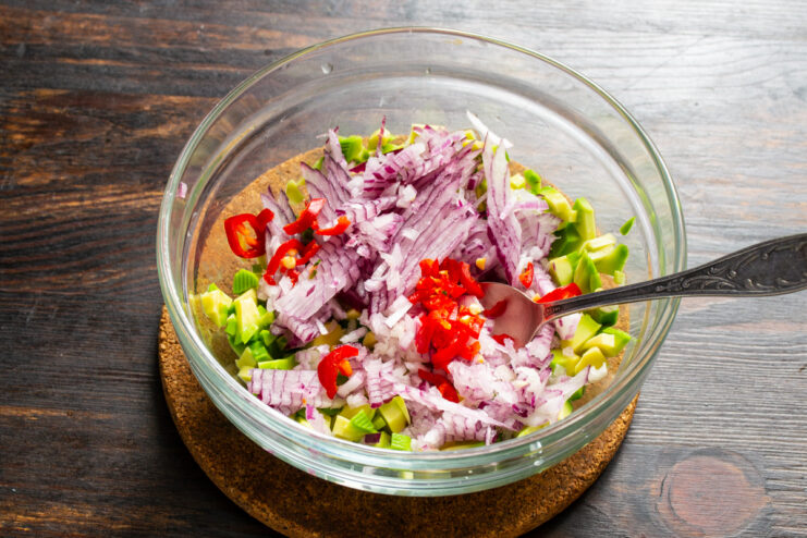 Incorporar el chile fresco Añadiendo trocitos de chile rojo picado al bol con guacamole