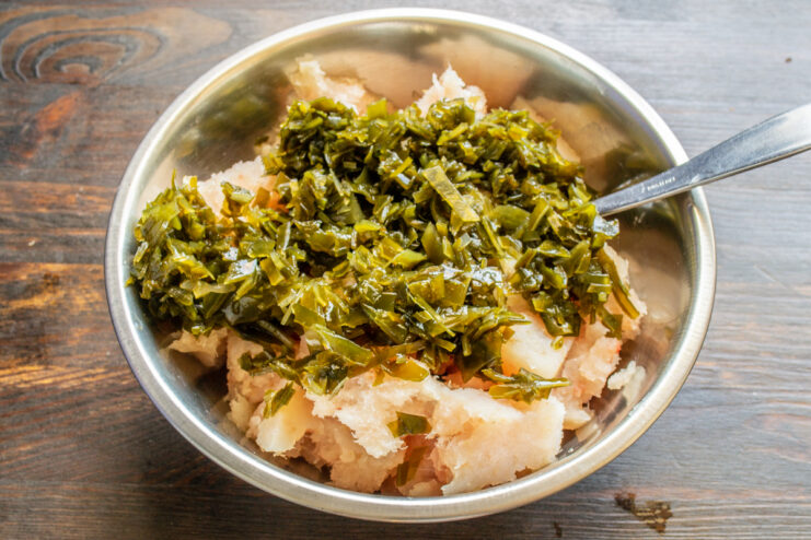 Mezcla del pescado con las algas Añadiendo algas finamente picadas al bol con el pescado