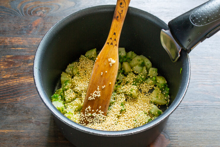 Quinoa mezclada con las verduras Quinoa añadiéndose y mezclándose con las verduras en el cazo
