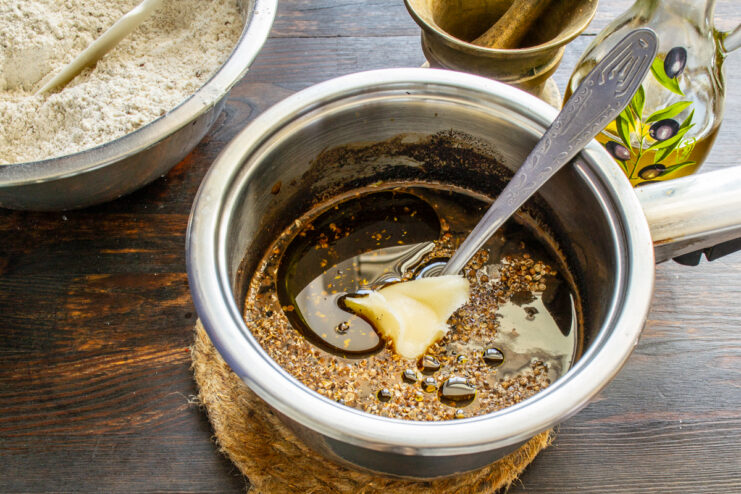 Miel para la masa Añadiendo miel a la mezcla templada de ingredientes en un cazo