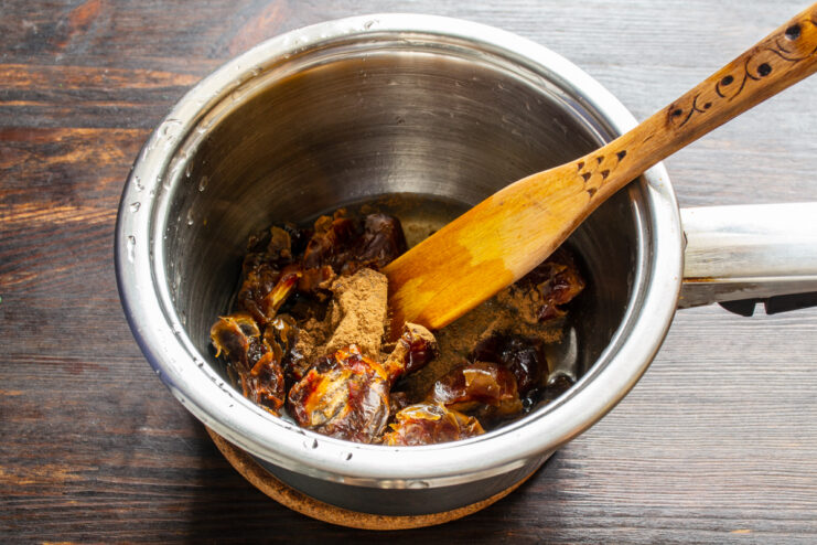 Especias para la salsa de dátiles Añadiendo canela molida a los dátiles dentro de un cazo