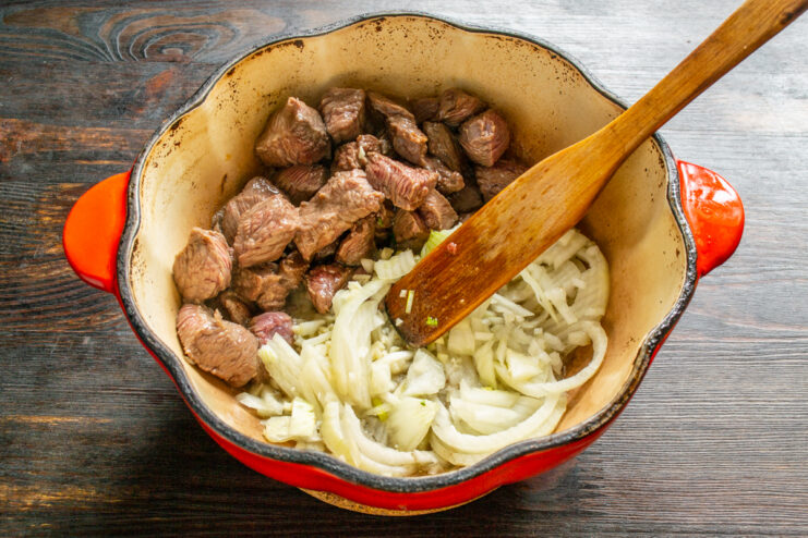 Añadiendo cebolla y ajo picados a la carne dorada