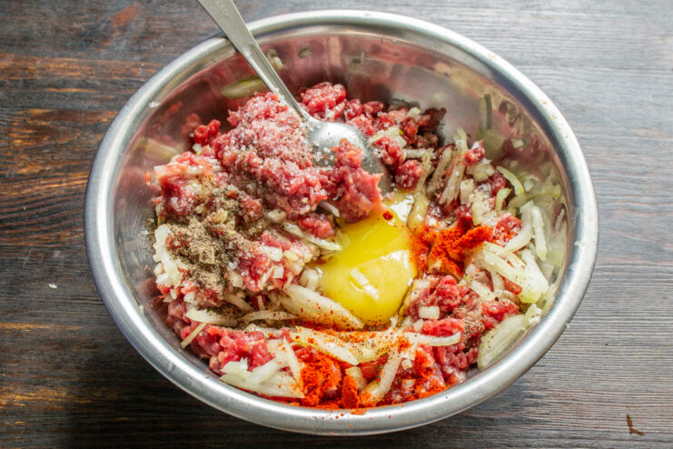 Añadiendo un huevo crudo y especias a la carne picada