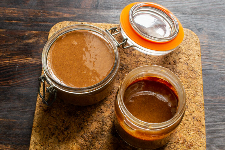 Crema lista en los botes Dos botes de cristal llenos de crema de cacahuete con chocolate terminada.