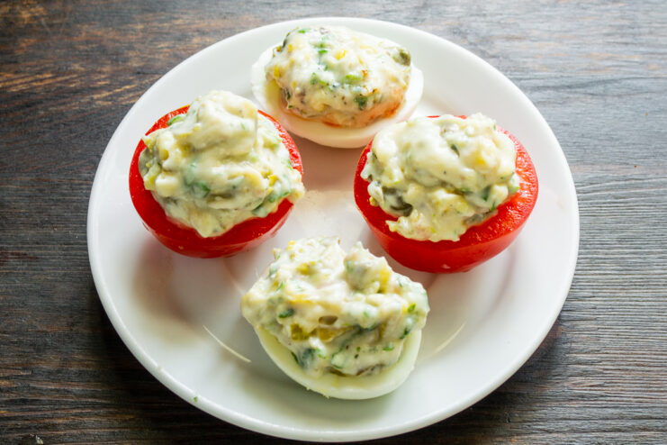Proceso de rellenar los huevos y tomates con una mezcla de queso