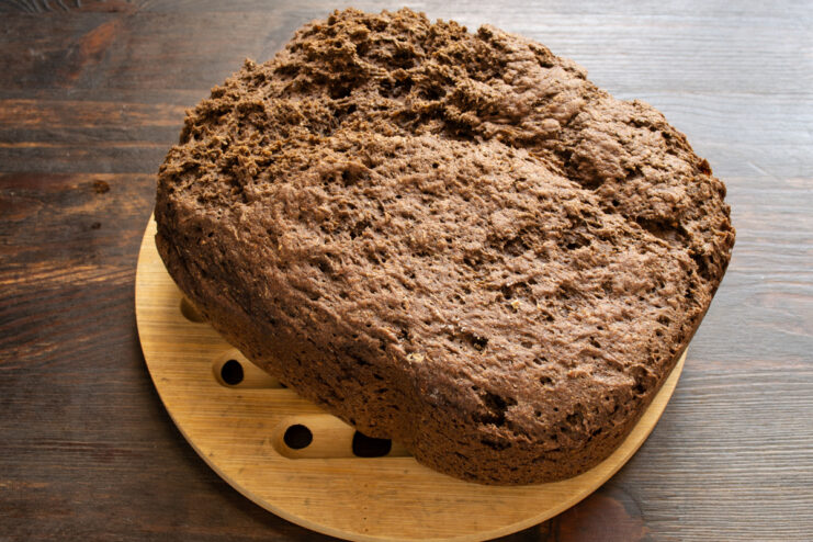 Pan recién horneado Hogaza de pan de lino horneada reposando sobre un soporte de madera