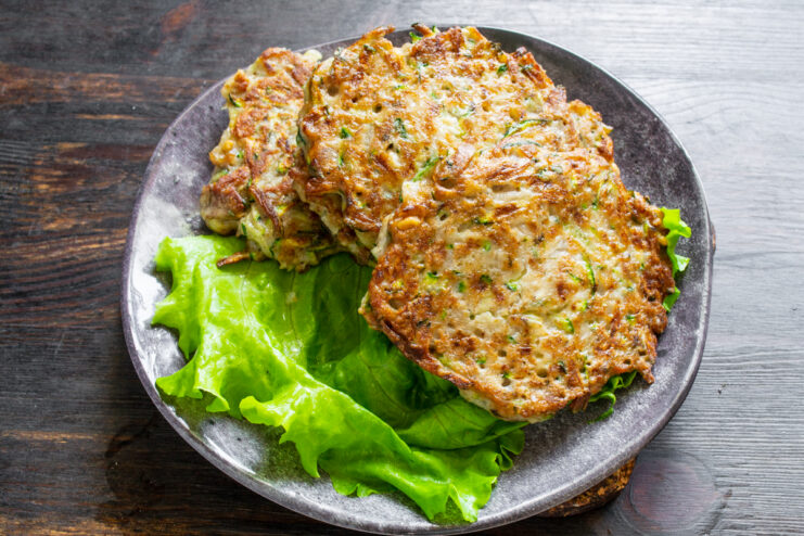 Presentación del plato Tortitas de calabacín servidas sobre hojas de lechuga fresca