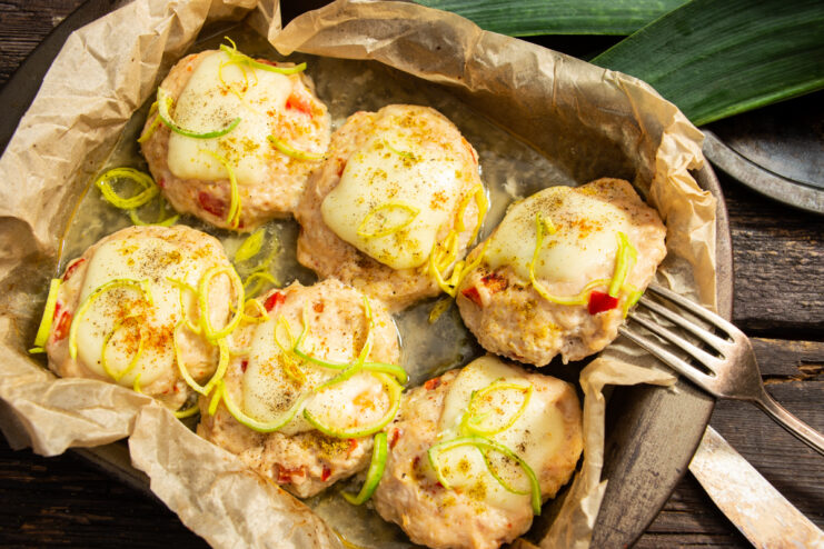 Albóndigas doradas con pimiento y queso fundido en una fuente para horno