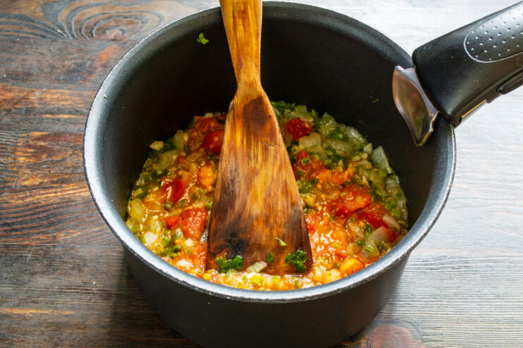 Guiso de la salsa de tomate Salsa de tomate casera espesa con trocitos de verdura cociendo en la sartén.