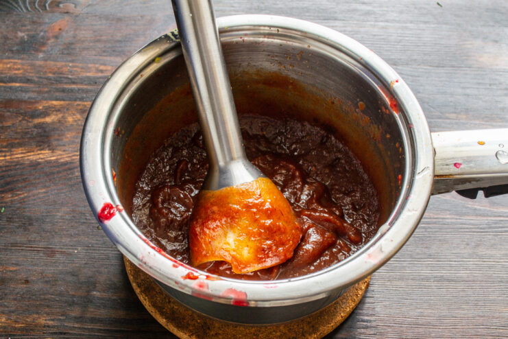 Triturado de la salsa Triturando la salsa de dátiles con una batidora de mano dentro de un cazo