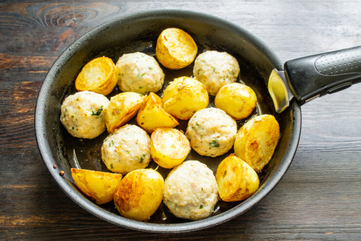 Albóndigas añadiéndose a las patatas doradas en la sartén