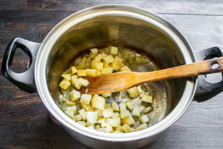 Dados de patata recién añadidos a la olla con la cebolla pochada.