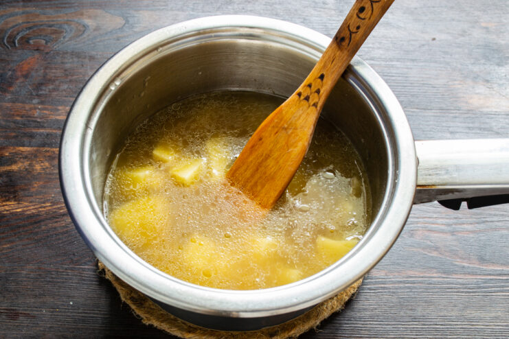 Caldo de pollo vertiéndose sobre las patatas y la cebolla en la olla