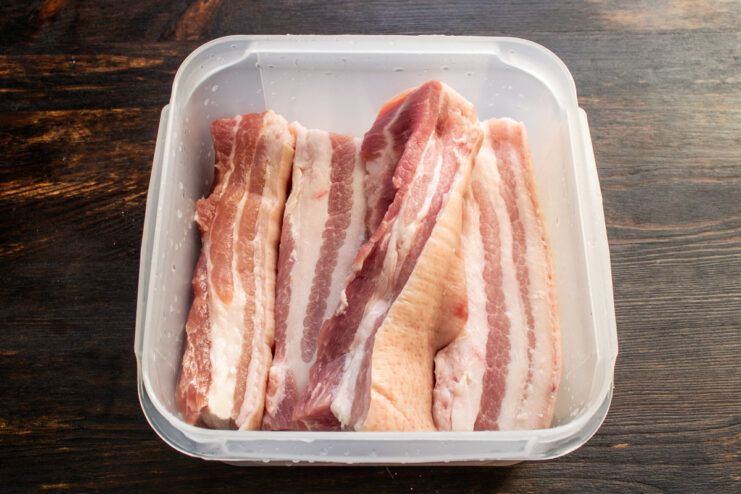 Trozos de panceta de cerdo dentro de un recipiente de plástico