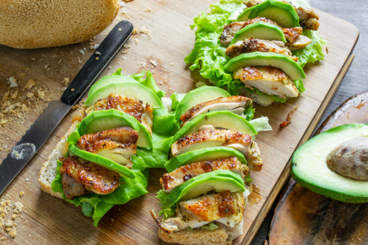 Láminas de aguacate fresco intercaladas entre los trozos de pollo en la tosta.