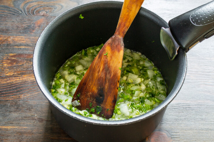 Pochado de la cebolla con caldo Verduras picadas cocinándose a fuego lento en una cazuela con un chorrito de caldo.