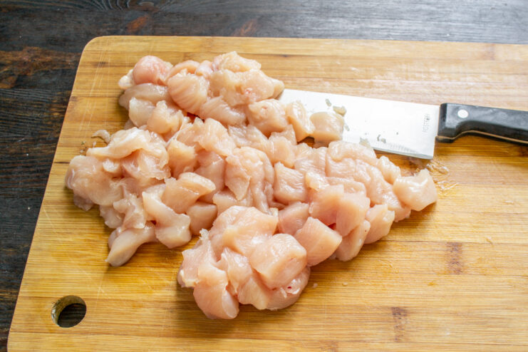 Preparando el pollo Dados de pechuga de pollo fresca sobre una tabla de cortar