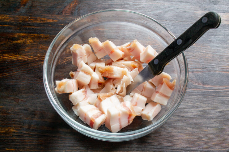 Dados de tocino curado servidos en un cuenco de cristal transparente