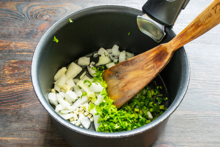 Sofrito de verduras para la salsa Cebolla, ajo y apio picados pochándose en una cazuela con aceite de oliva.