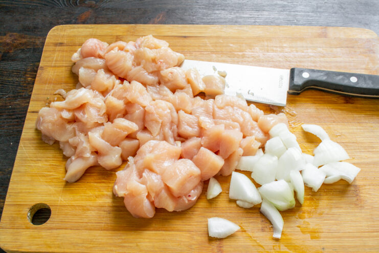 Incorporando la cebolla a la mezcla Cebolla picada mezclada con los dados de pollo crudo