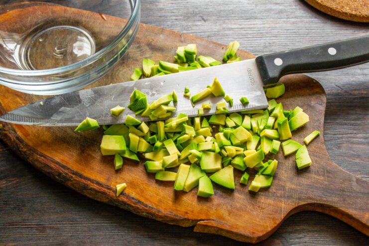 Trocear la pulpa del aguacate Cortando un aguacate en dados sobre una tabla de cocina