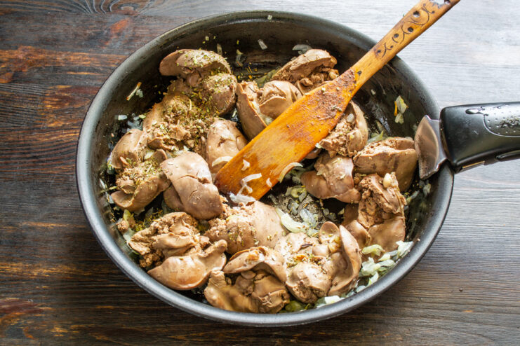Sofrito con especias Hígados de pollo dorándose en la sartén con cebolla y hierbas provenzales