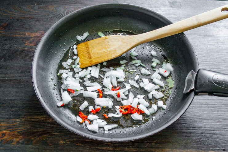 Sofrito de cebolla y chile Cebolla picada y aros de chile rojo sofriéndose en una sartén
