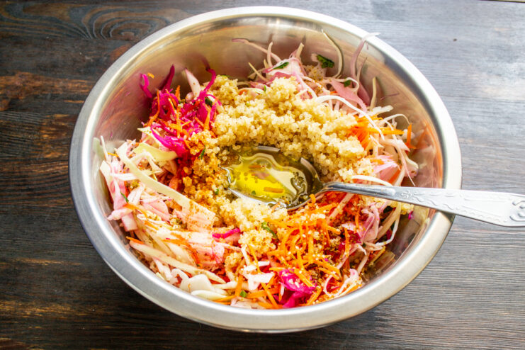 Chorro de aceite de oliva cayendo sobre la ensalada de quinoa y verduras.