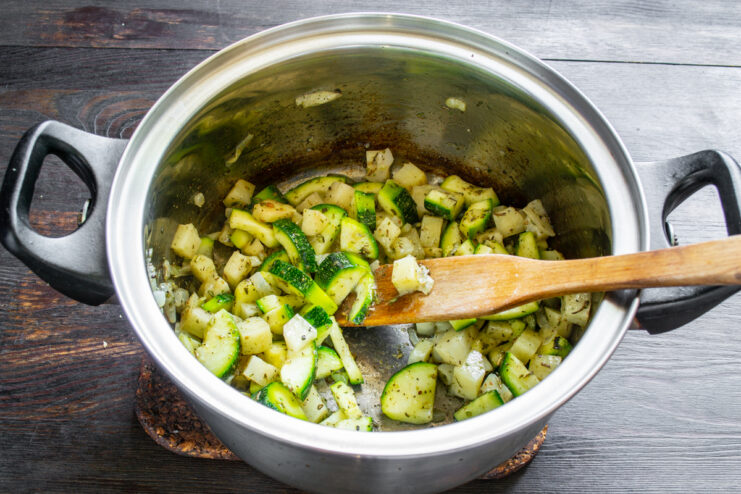 Verduras mezcladas con especias rehogándose en aceite de oliva dentro de la cazuela.