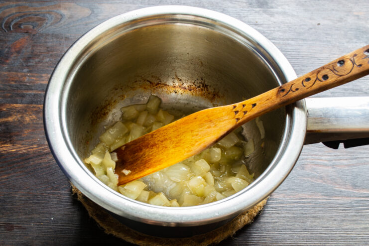 Cebolla transparente cocinándose a fuego lento con un poco de caldo en la olla