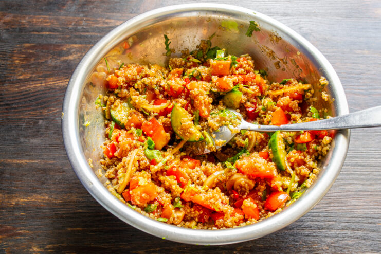 Mezclando la ensalada de quinoa con una cuchara grande en un bol