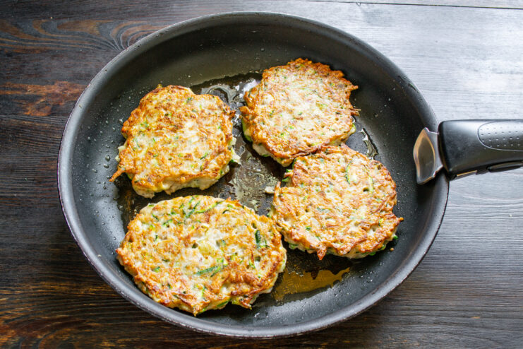 Fritura de las tortitas Tortitas de calabacín dándose la vuelta en una sartén con aceite