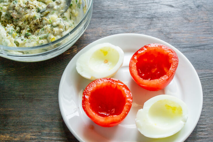 Mitades de huevo cocido y tomates vaciados listos para rellenar