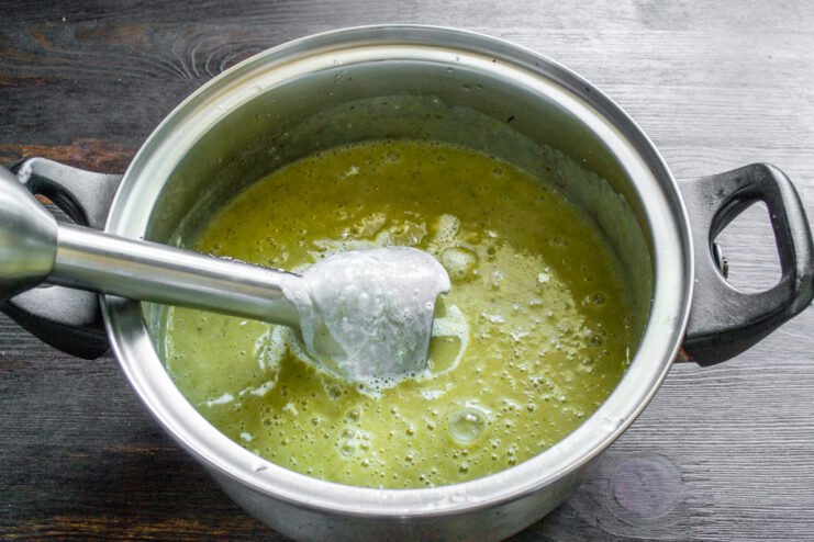 Batidora de mano triturando las verduras dentro de la olla hasta formar una crema sedosa.