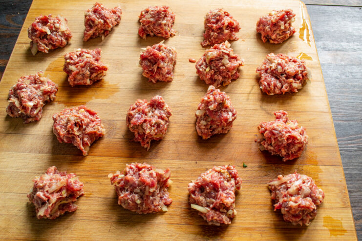 Bolitas de carne cruda sobre una tabla de cortar de madera