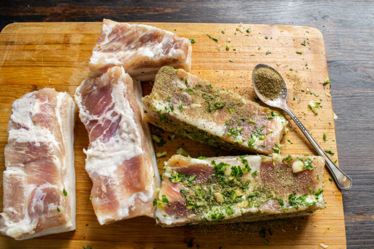 Espolvoreando la panceta con laurel y comino molidos