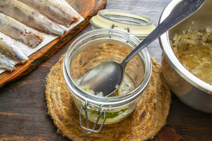 Alternancia de ingredientes Añadiendo una capa de cebolla marinada sobre los trozos de arenque