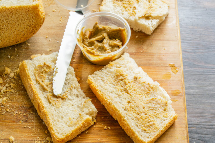 Cuchillo untando mostaza casera sobre una rebanada de pan de masa madre.