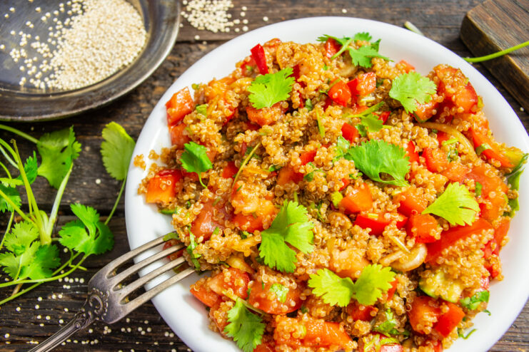 Ensalada de quinoa con tomates y pimiento rojo dulce servida en un plato blanco
