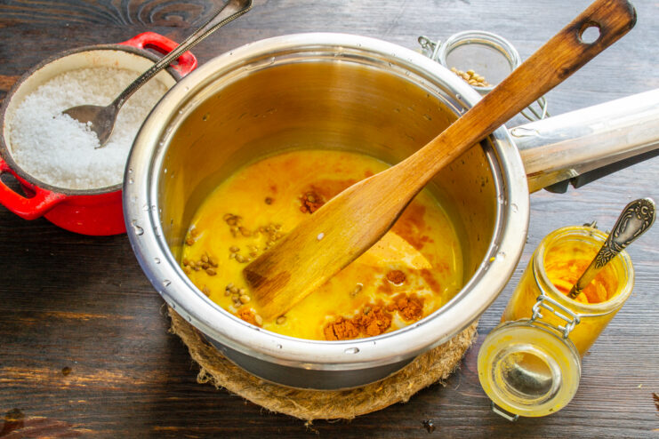 Semillas de cilantro añadiéndose a la mezcla de leche y cúrcuma