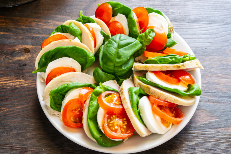 Presentación de la ensalada caprese con pollo en forma de abanico sobre un plato blanco