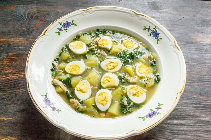Sopa de ortigas servida en un plato hondo y decorada con mitades de huevos de codorniz