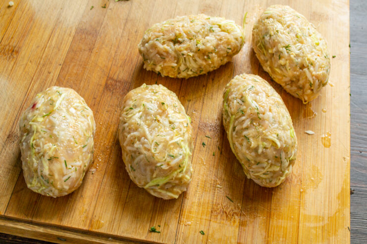Dar forma a los rollitos Rollitos de carne con forma ovalada sobre una tabla de madera